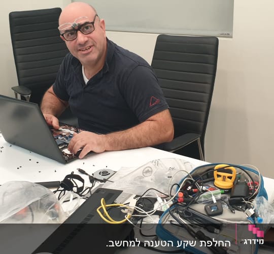 אדם מתקן מחשב נייד עם כלים על שולחן